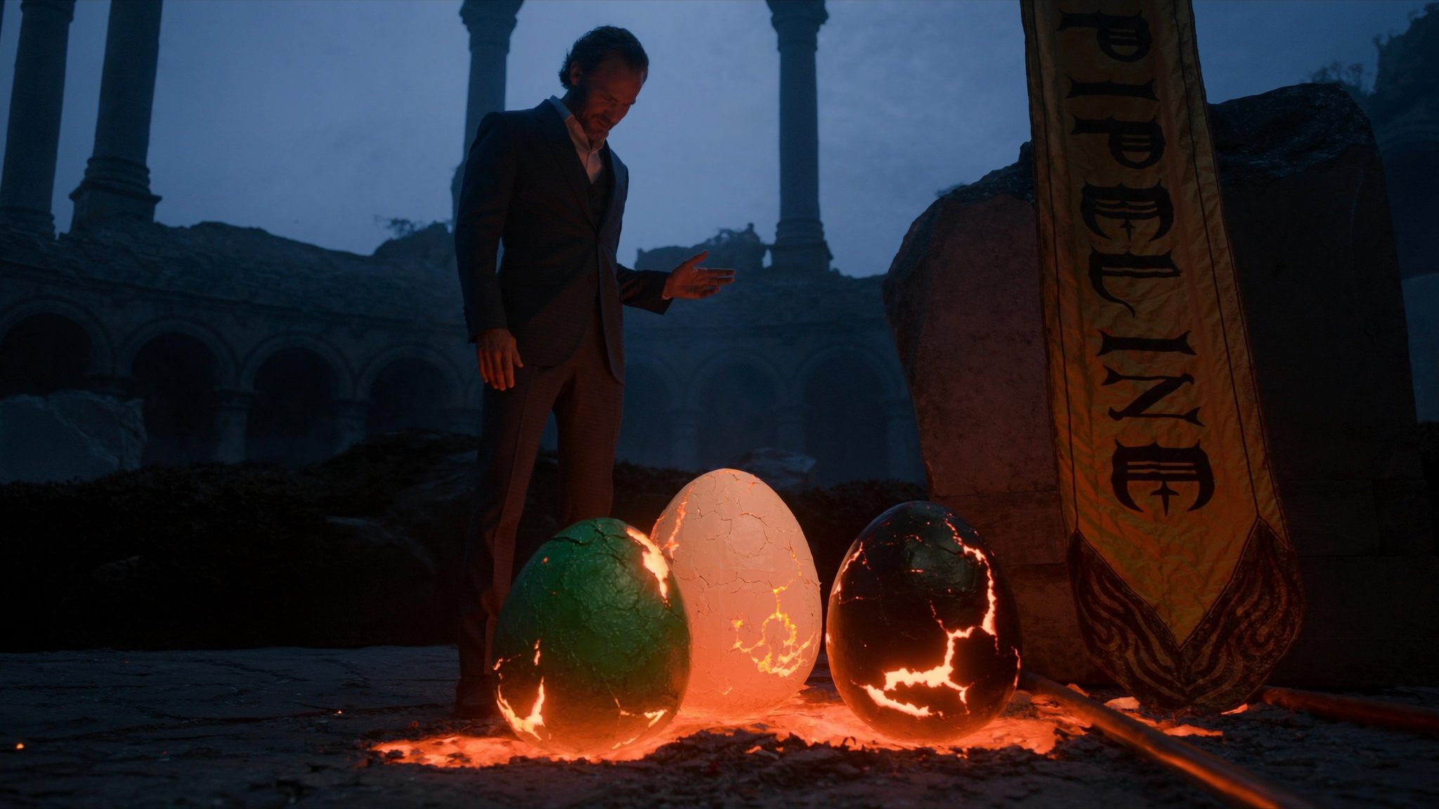 Operator standing in the ruined Dragonpit beside three glowing dragon eggs about to hatch. Heraldic banner reads PIPELINE.