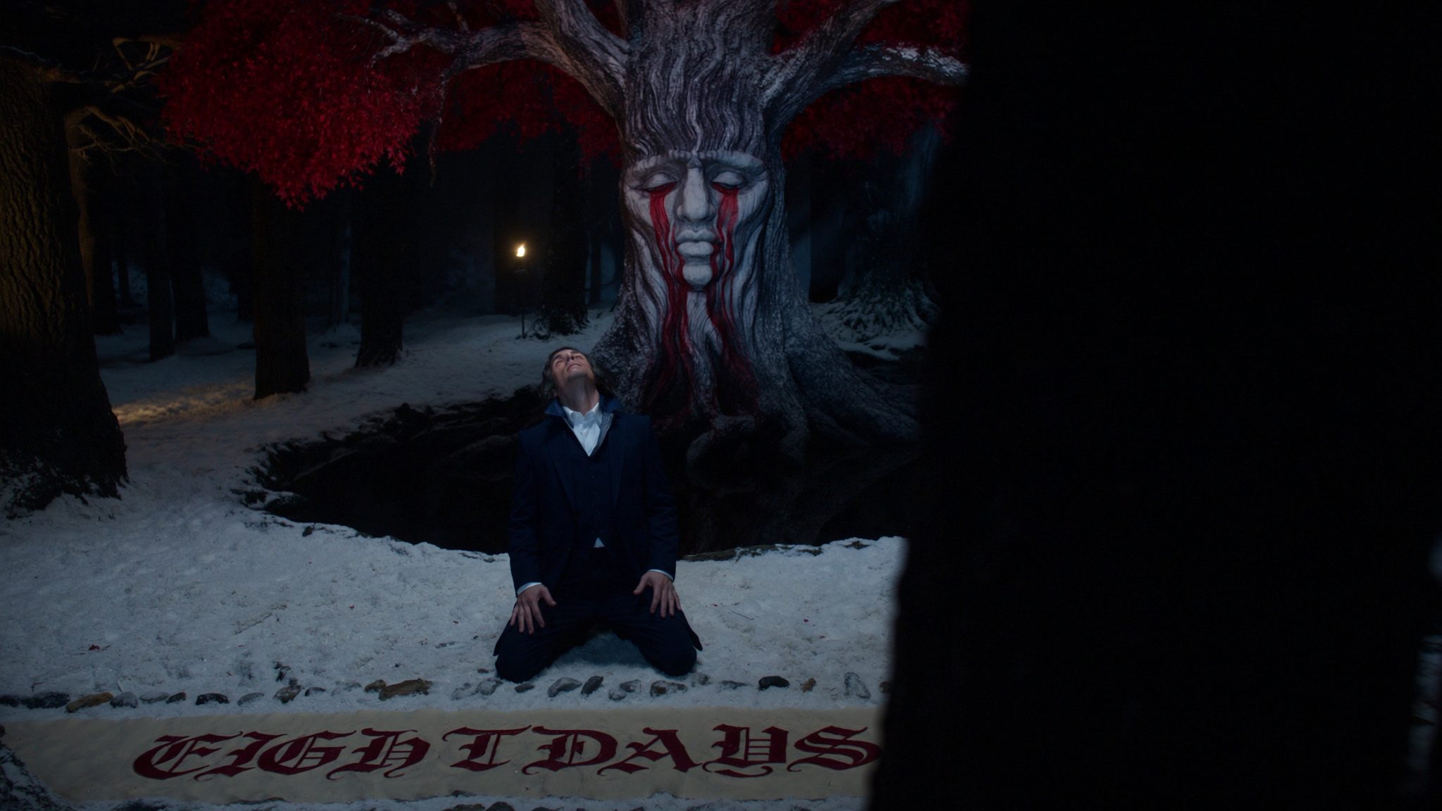 Operator kneeling at the Winterfell weirwood heart tree, eight dark stones laid before him in snow. Heraldic banner reads EIGHT DAYS.