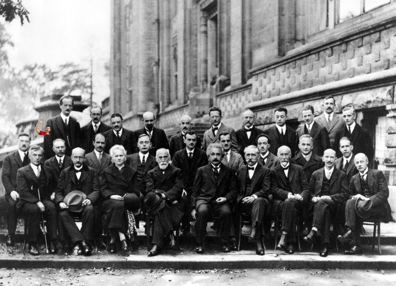 The 1927 Solvay Conference of physicists, with a colour figure in a red shirt leaning into the back row on the left, waving.